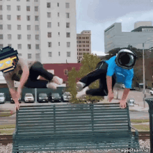 two men are jumping over a park bench with ageofsam.io written on the bottom right