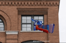 a brick building with a cartoon character flying out of a window