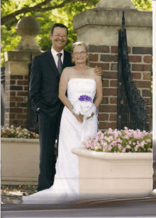 a bride and groom posing for a photo in front of a brick wall