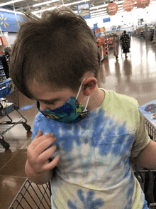 a young boy wearing a face mask sits in a shopping cart