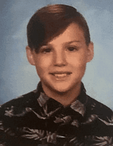 a young boy wearing a hawaiian shirt is smiling for the camera