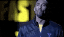 a man wearing a blue jacket and a yellow shirt is standing in the dark .