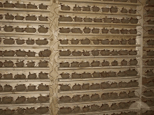 a wall filled with shelves filled with lots of clay pots .