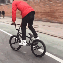 a man in a red jacket is riding a bicycle