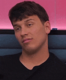 a close up of a man 's face with a pink wall in the background