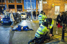 a police officer is kneeling down next to a man who is laying on the ground