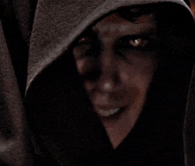 a close up of a person with a hood on their head and glowing eyes .