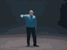 a bald man in a blue sweater is pointing up