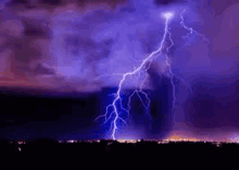 a lightning bolt is strikes in the sky over a city at night .