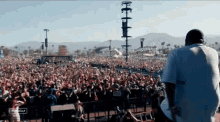 a man stands in front of a crowd at a festival with the words " coachella " on the bottom right