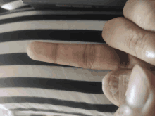 a person 's finger is laying on a black and white striped cloth