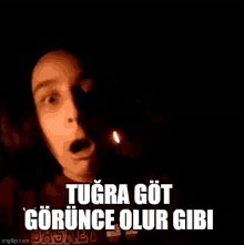 a man is standing in the dark with a candle in front of him and says tugra got gorunce olur gibi