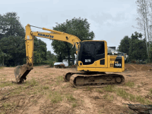 a komatsu pc 130 excavator is parked in a dirt field