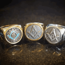 three rings with masonic symbols on them are lined up on a table