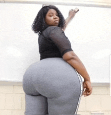 a woman with a very large butt stands in front of a white board