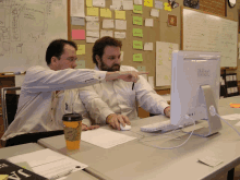 two men looking at a computer monitor with the word imac on it