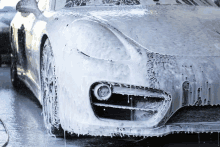 a car is covered in foam and water and is being cleaned