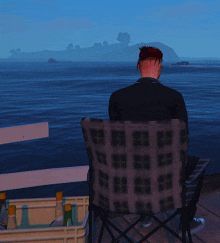 a man is sitting in a chair looking out over the ocean