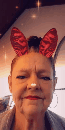 a woman with red bunny ears on her head making a face