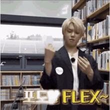 a man in a suit is standing in front of a bookshelf in a library and flexing his arms .