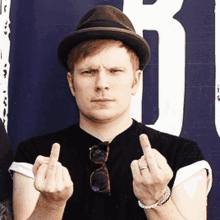 a man wearing a hat and sunglasses shows his middle finger