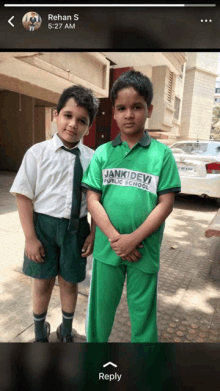 two boys are posing for a picture and one is wearing a shirt that says janki devi public school on it