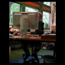 a man sits at a desk in front of a computer monitor with the name bathfield on the bottom left