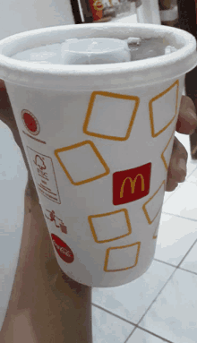 a person is holding a mcdonald 's cup with a lid