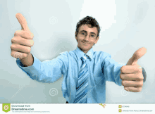 a young man in a blue shirt and tie is giving two thumbs up