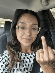 a woman with glasses and a ring is giving the middle finger