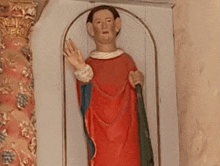 a statue of a man in a red robe is in a niche on a wall