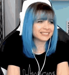 a woman with blue hair is sitting in a chair wearing headphones .