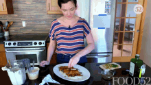 a woman in a striped shirt is preparing food in a kitchen with a bottle of food52 on the counter