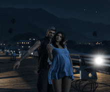 a man and a woman are posing for a photo on a pier at night