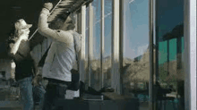 a man is cleaning a window with a hose while a woman looks on .