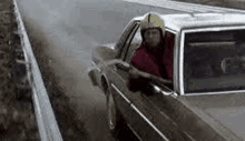 a man in a helmet is driving a car on a dirt road .