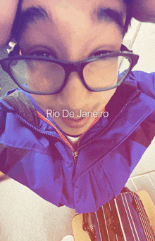 a person wearing glasses and a blue jacket with rio de janeiro written on the bottom right