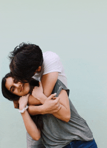 a man is holding a woman in his arms and kissing her on the forehead .