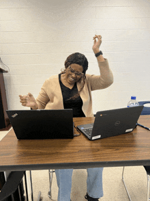 a woman sitting at a table with two dell laptops