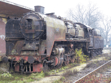 an old rusty train sits on the tracks with graffiti on the side of it