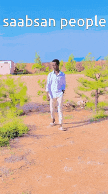 a man in a white shirt and white pants is walking down a dirt road with the words saabsan people written above him