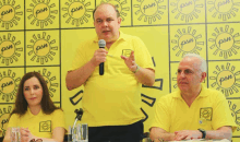 a man speaking into a microphone in front of a wall that has pan written on it