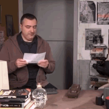 a man sits at a desk with a bottle of water and a stack of books including one that says vcrs