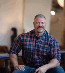 a man wearing a plaid shirt is sitting down