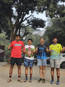 four men are posing for a picture and one of them is wearing a shirt that says ' super dry ' on it