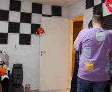 a man in a purple shirt is standing in a room with checkered walls