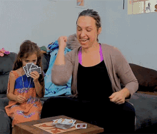 a woman and a little girl are playing a game of cards and the little girl is holding a card with the letter z on it