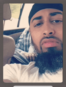 a man with a beard is sitting in a car and looking at the camera