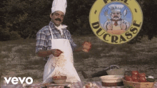 a man in a chef 's hat and apron is standing in front of a ducrasse sign