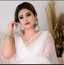 a woman in a white saree and silver earrings